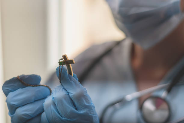 Health worker holding a religious symbol.